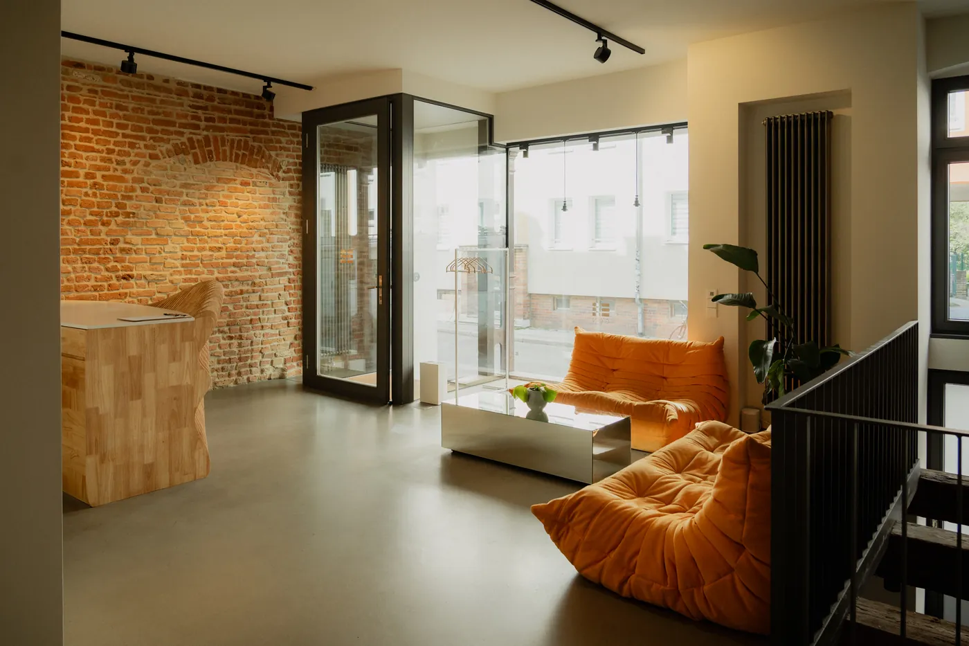 GON Berlin reception room with a sculpted timber desk and orange Togo seating in warm daylight