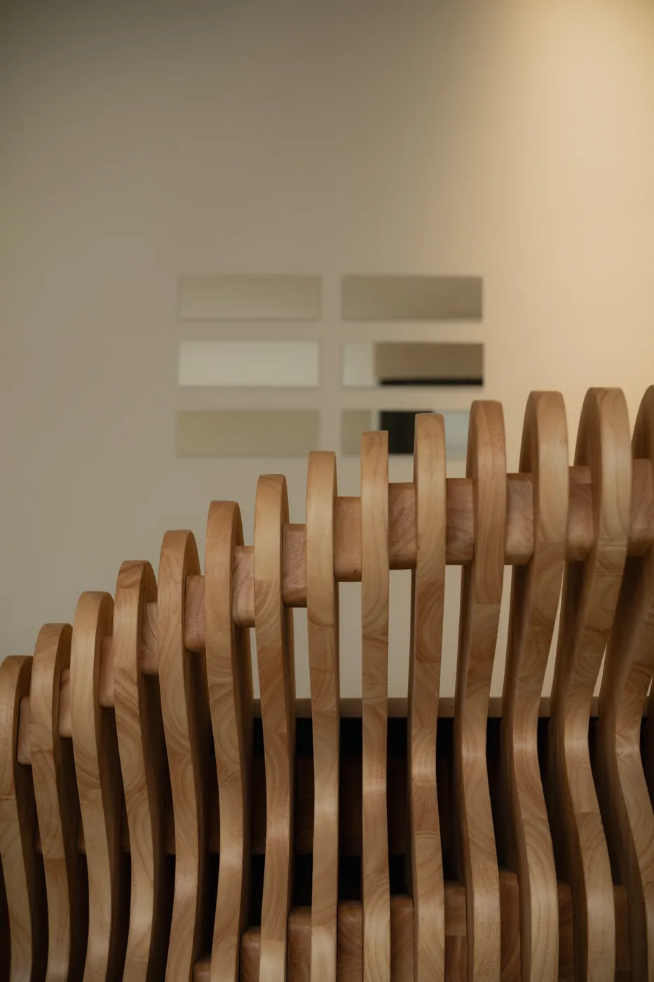 Detail of the sculpted wave-wood bench beside trigram wall art at GON Berlin