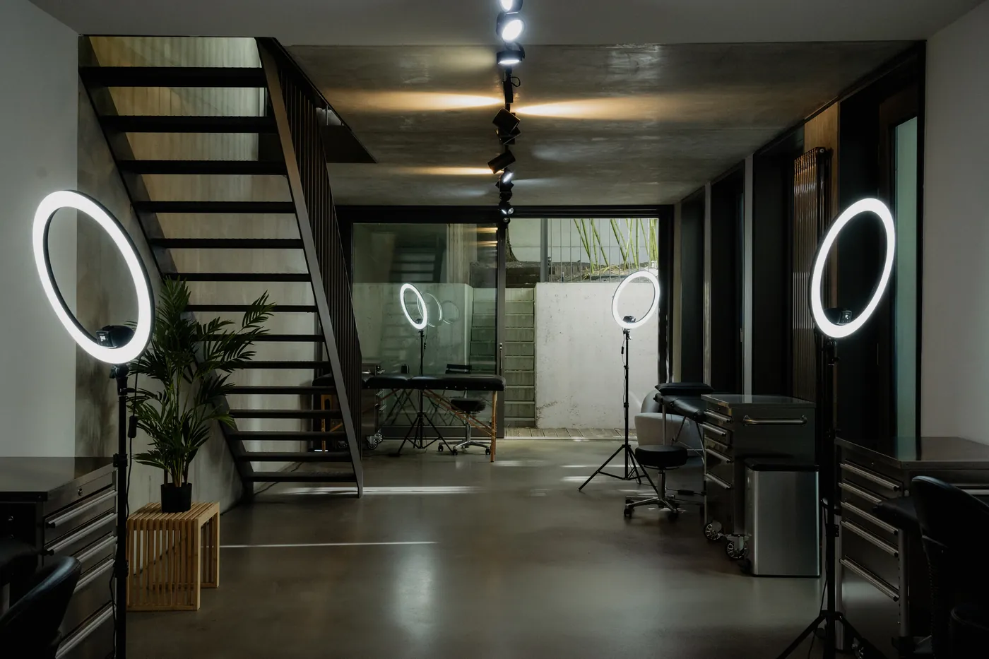 Tattoo studio floor at GON Berlin with ring lights, steel stations and a black steel staircase