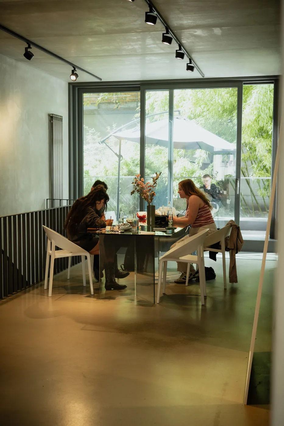 Two clients drawing at a mirrored table beside the garden window at GON Berlin